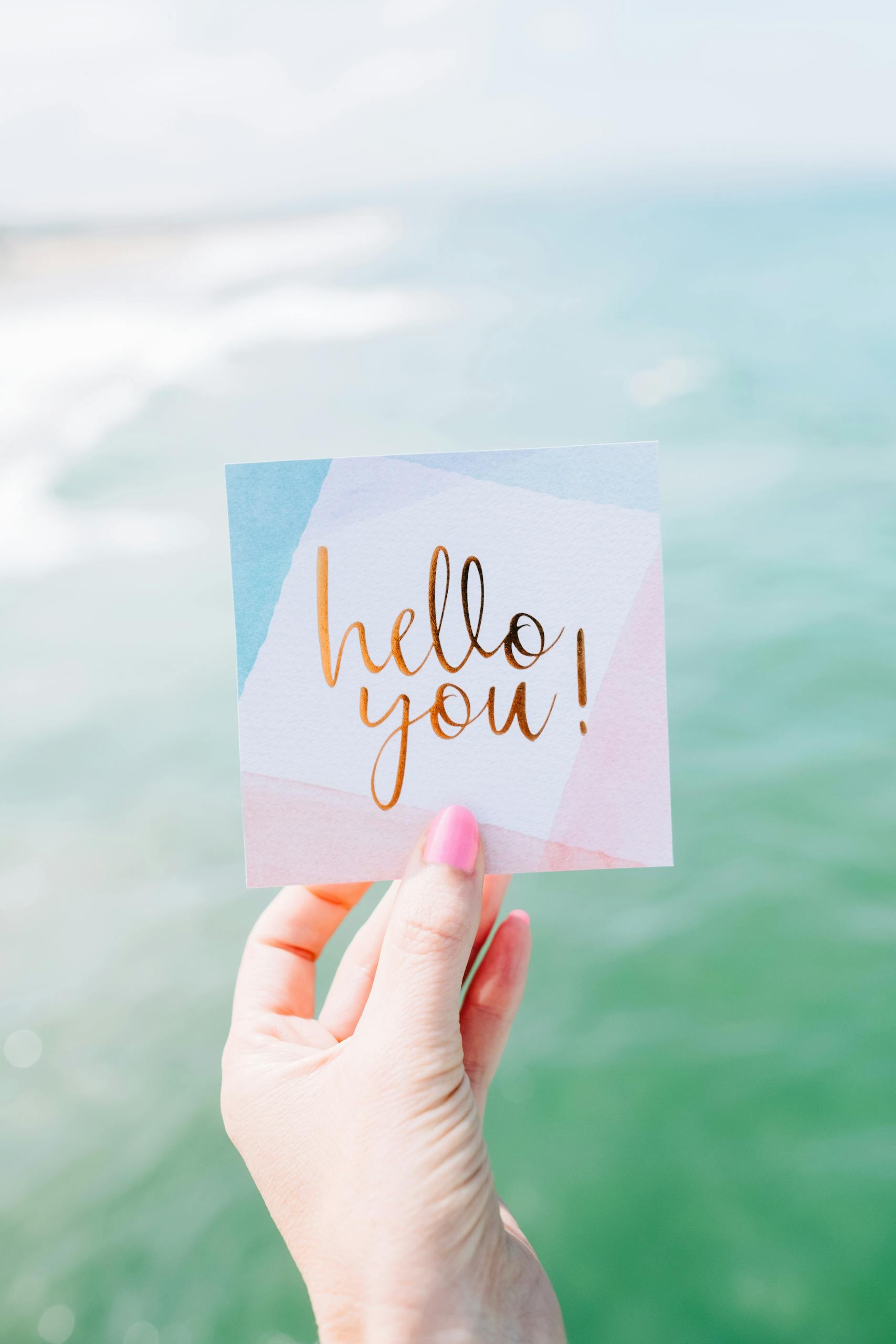 A vibrant greeting card with 'hello you!' against a seaside backdrop, conveying positivity.